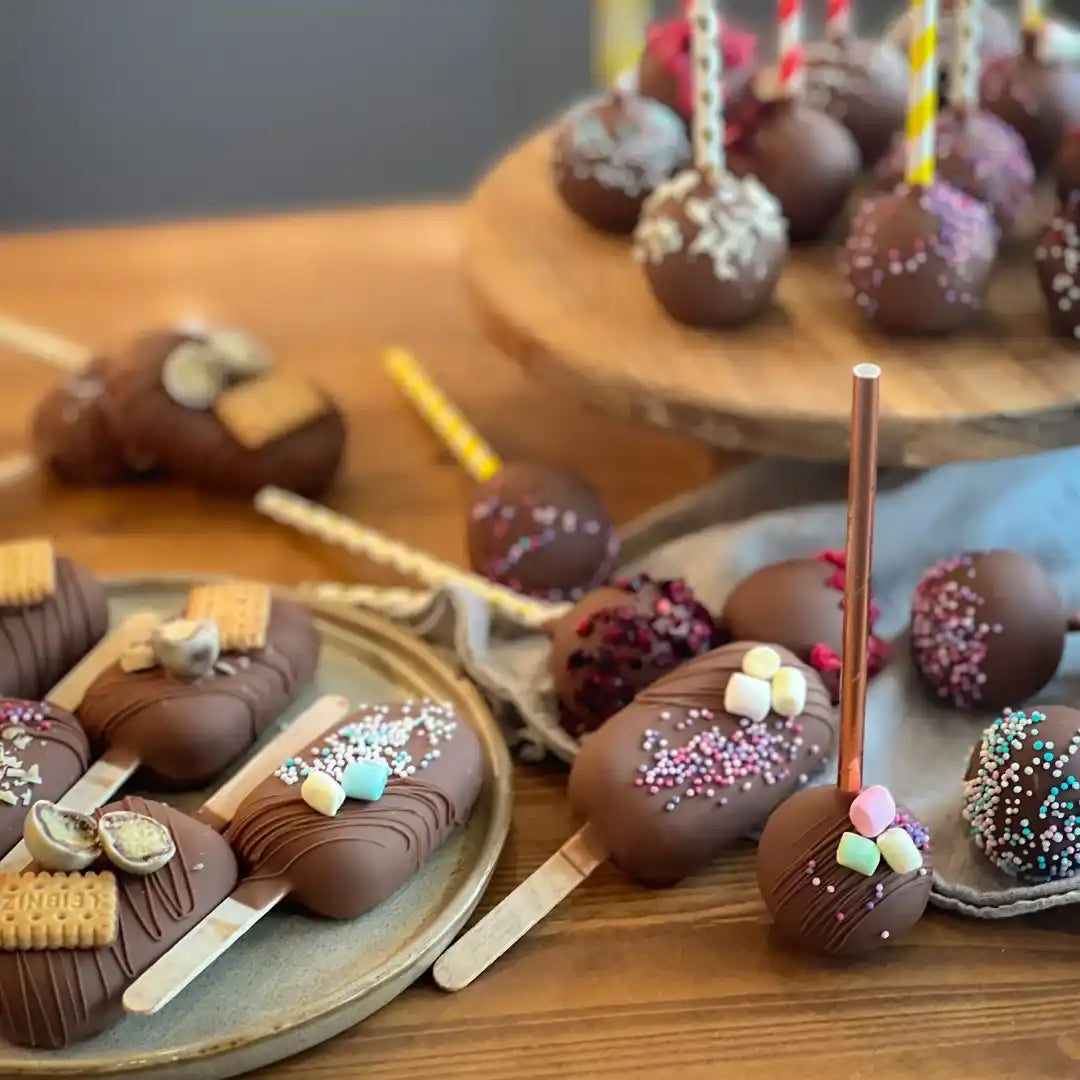 Segatud šokolaadiga kaetud kookosvõrrat ja šokolaadiga kaetud kingitused pulgadel, kaunistatud erinevate lisanditega.